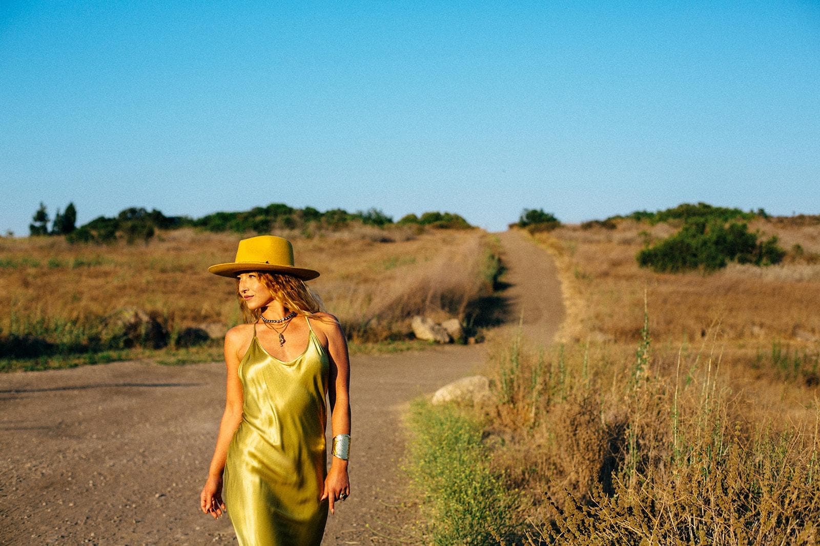 Aura Massage LA founder outdoors in a gold dress and hat